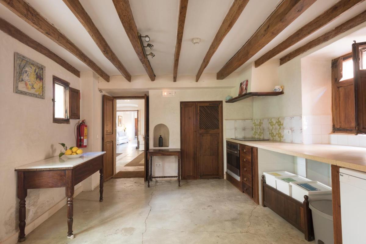 una cocina con techos de madera y una mesa. en Sa Bisbal - Turismo de interior, en Selva