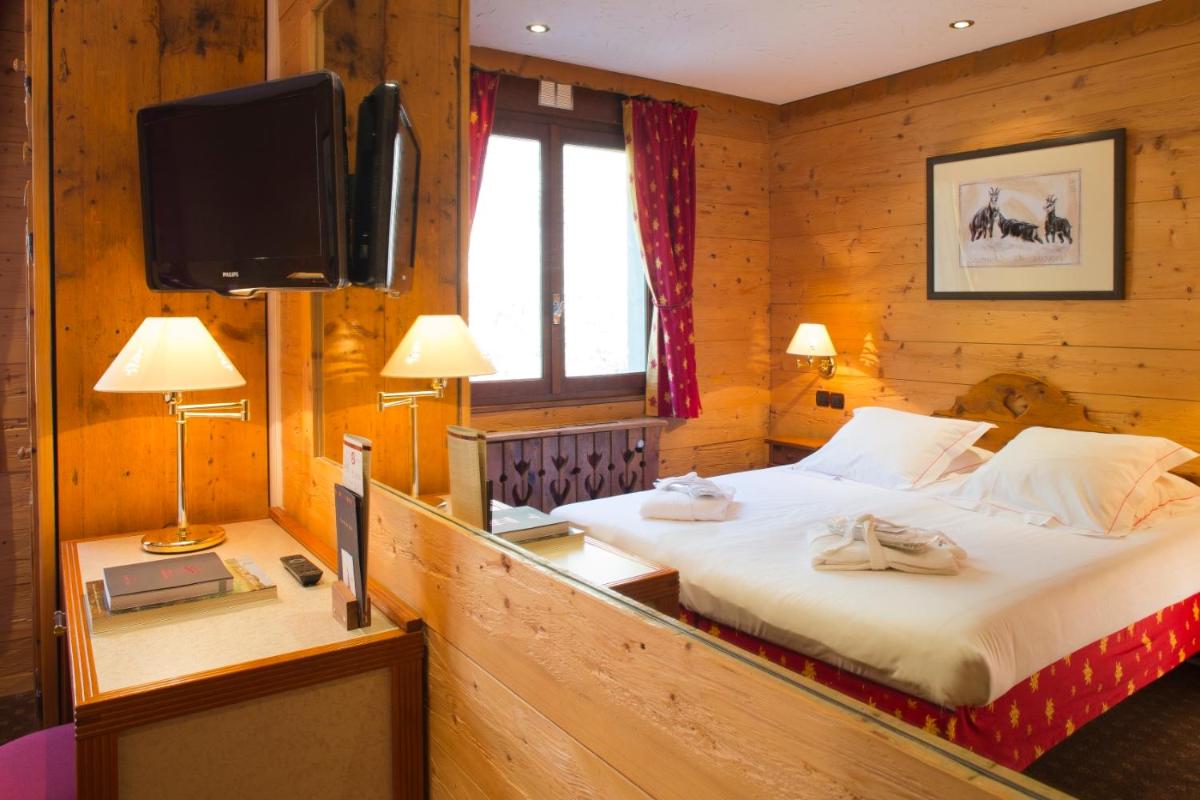 une chambre avec un lit et une télévision dans une pièce dans l'établissement Carlina, à La Clusaz