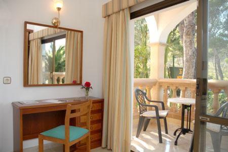 Una oficina en casa con un escritorio y un espejo. en Hotel Cala Gat, en Cala Ratjada