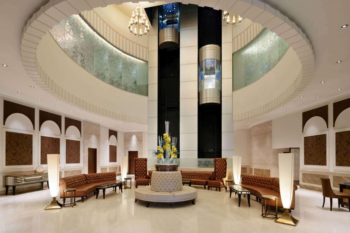 a lobby with chairs and a fountain in a building at Ramada Plaza Chennai in Chennai