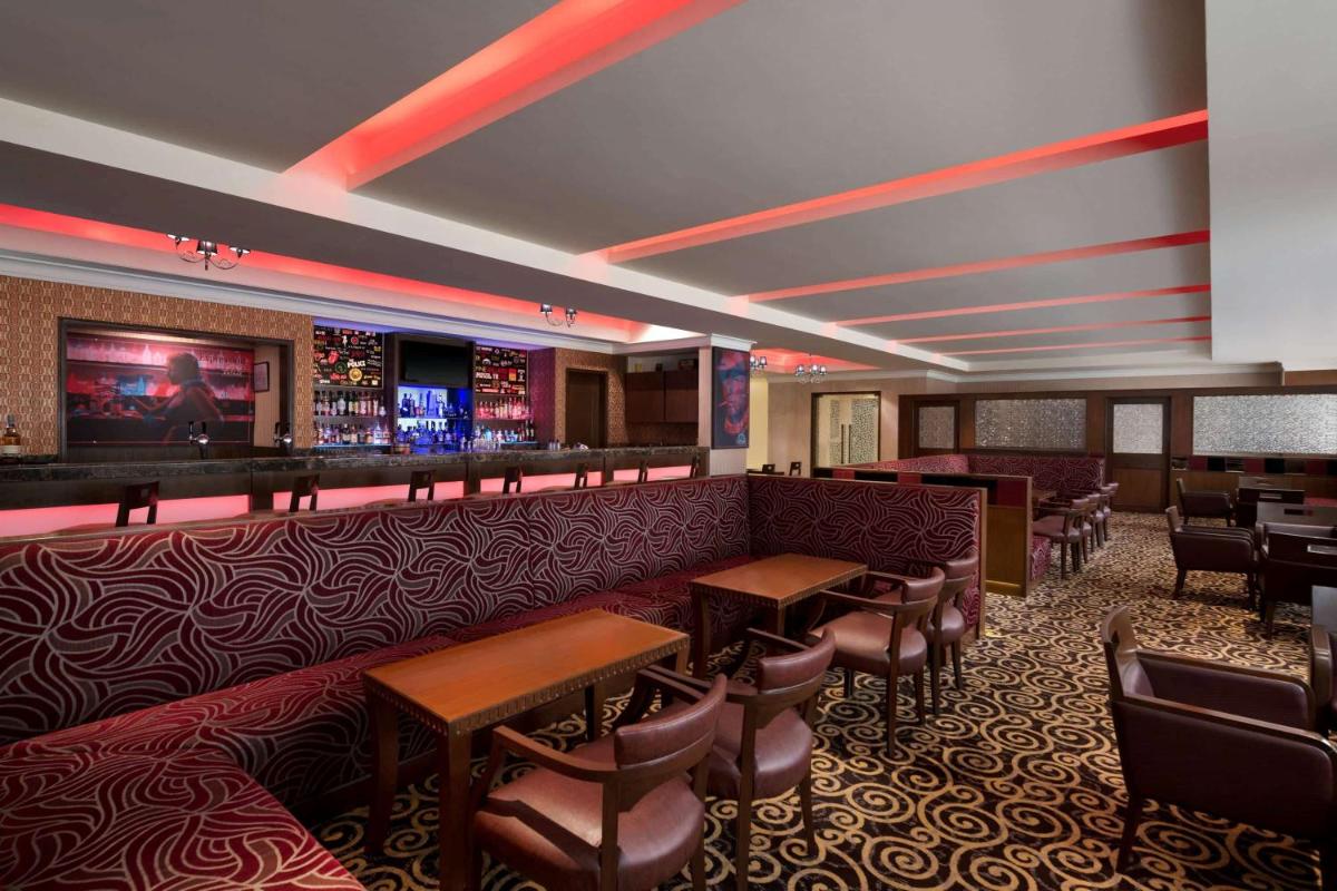 a restaurant with a bar and tables and chairs at Ramada Plaza Chennai in Chennai