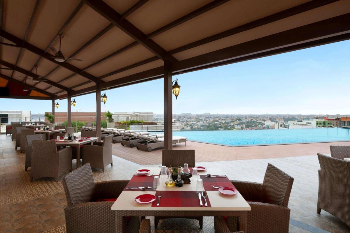 a restaurant with tables and chairs and a pool at Ramada Plaza Chennai in Chennai