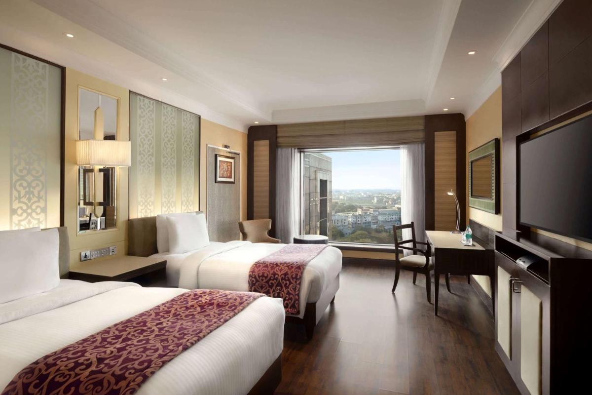 a hotel room with two beds and a large window at Ramada Plaza Chennai in Chennai
