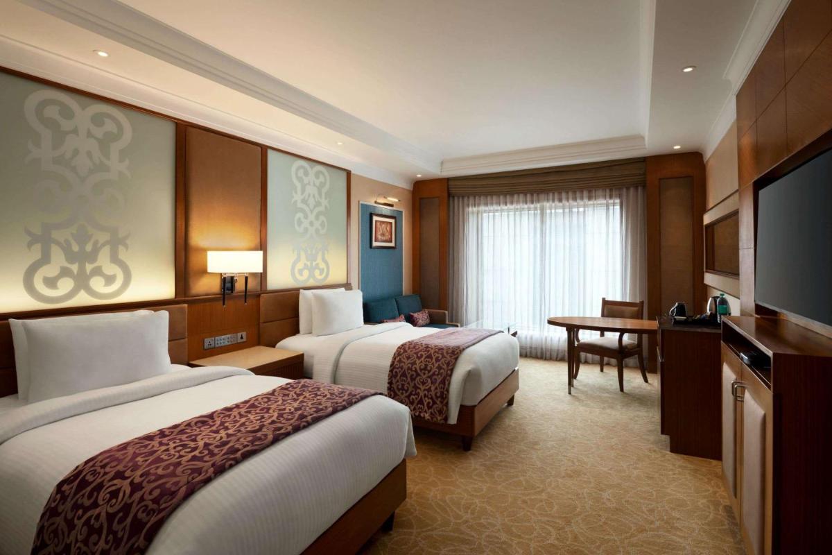 a hotel room with two beds and a television at Ramada Plaza Chennai in Chennai