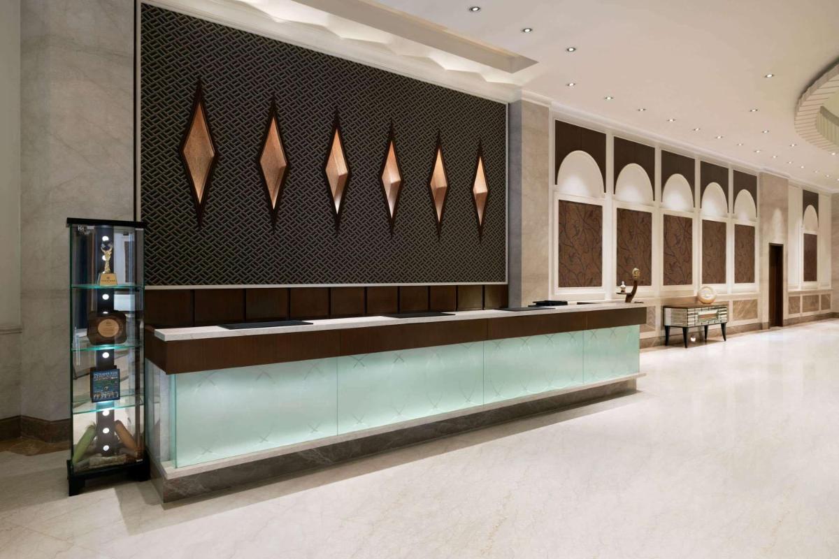 a lobby with a long counter in a building at Ramada Plaza Chennai in Chennai