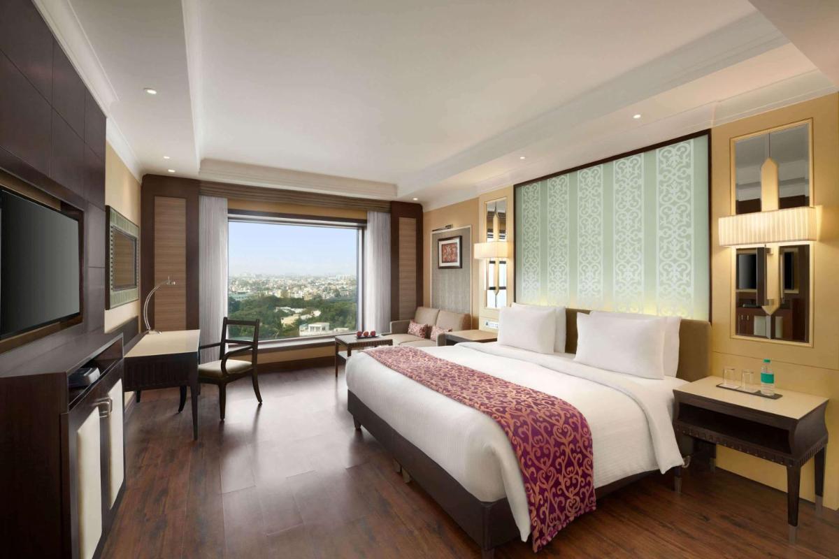 a hotel room with a large bed and a large window at Ramada Plaza Chennai in Chennai
