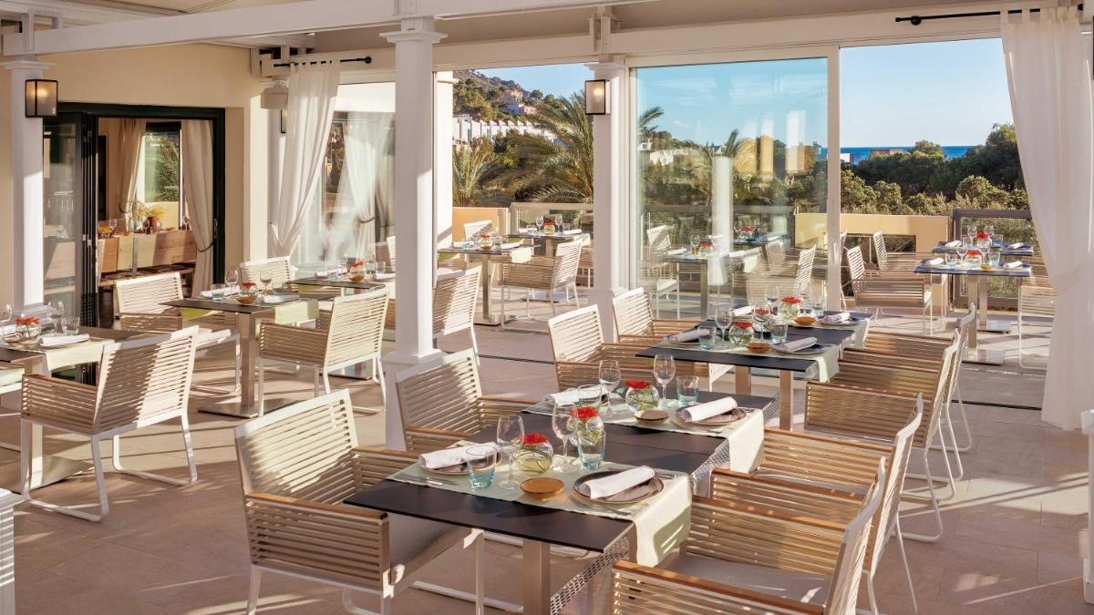 Un restaurante con mesas y sillas en un patio. en Steigenberger Hotel and Resort Camp de Mar, en Camp de Mar