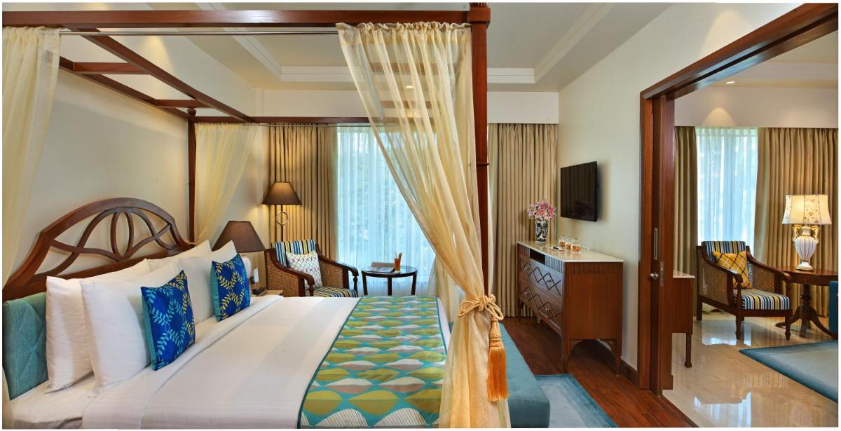 a bedroom with a canopy bed and a living room at Fortune Miramar, Goa - Member ITC Hotels' Group in Panaji a bedroom with a canopy bed and a living room at Fortune Miramar, Goa - Member ITC Hotels' Group in Panaji