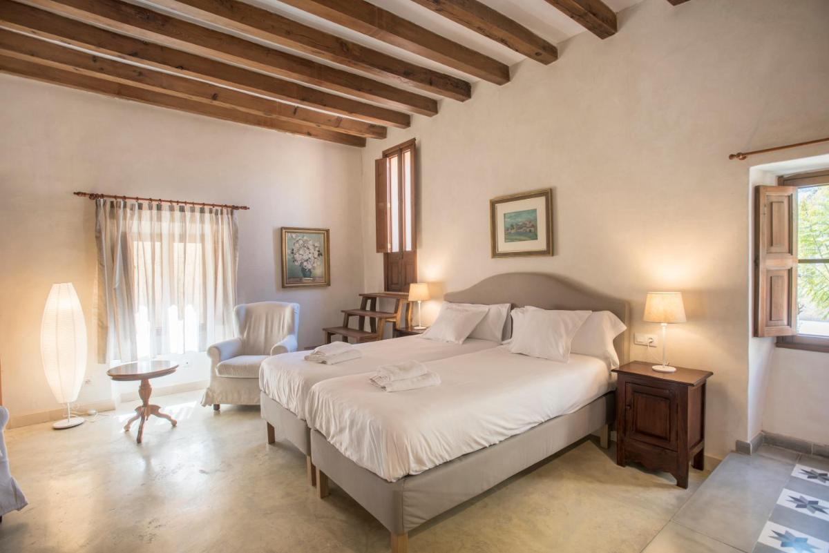 Un dormitorio con una gran cama blanca y una silla. en Sa Bisbal - Turismo de interior, en Selva