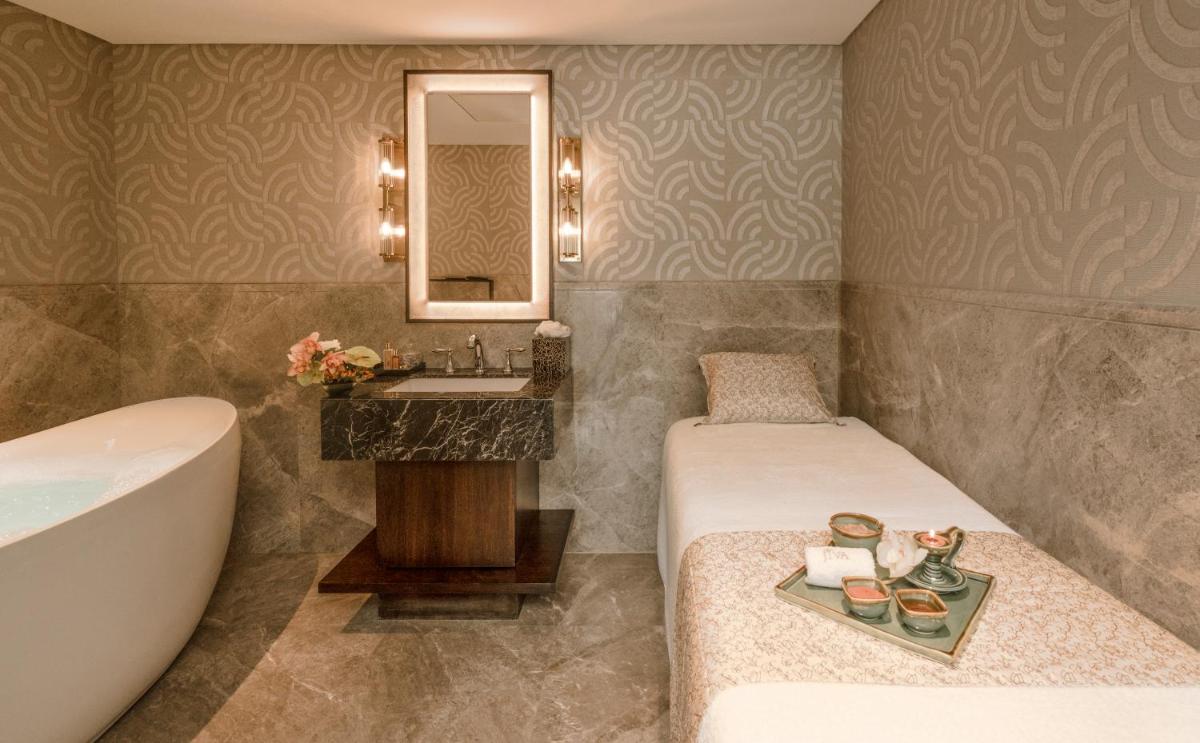 a bathroom with a tub and a bed and a sink at Taj Coromandel in Chennai