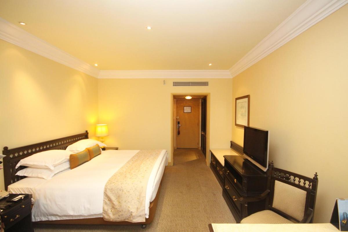a hotel room with two beds and a flat screen tv at Taj Bengal in Kolkata