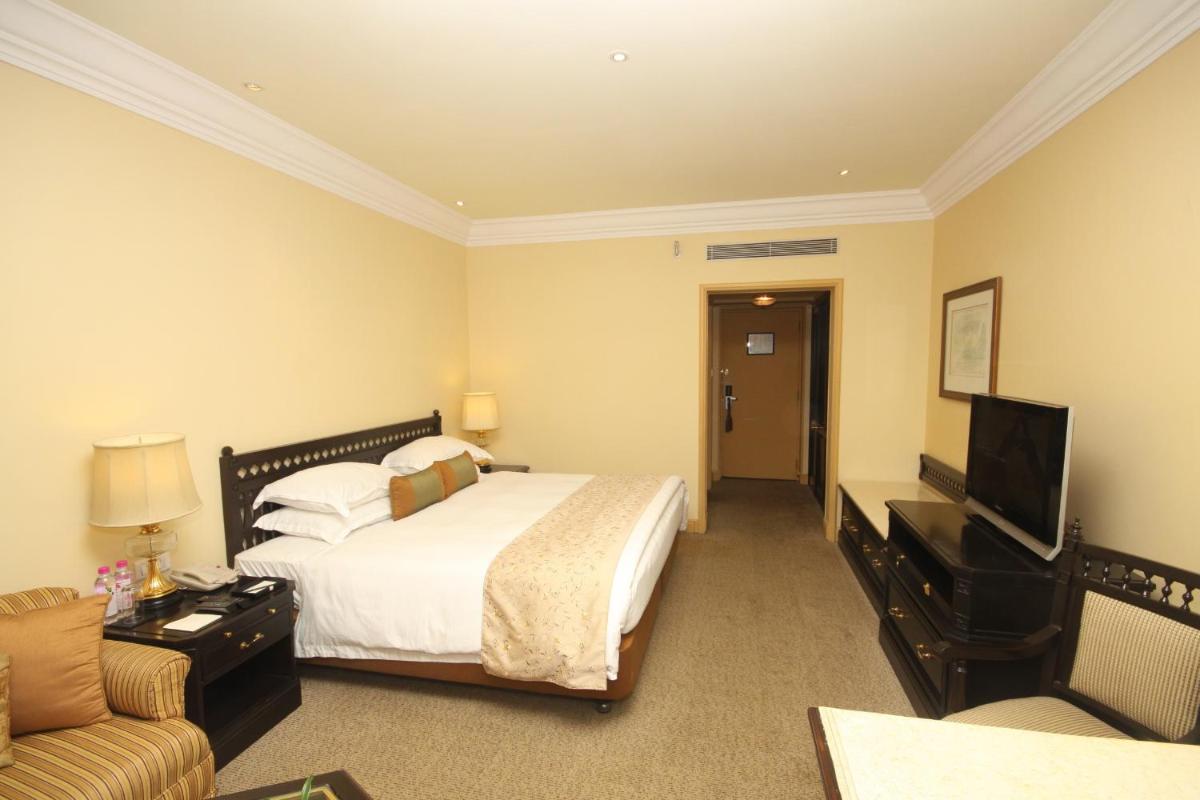 a hotel room with a bed and a flat screen tv at Taj Bengal in Kolkata