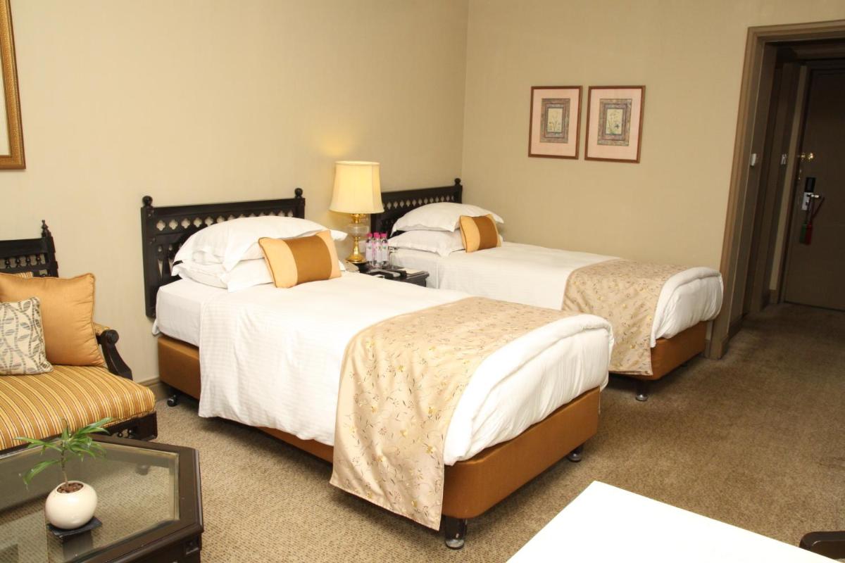 a hotel room with two beds and a couch at Taj Bengal in Kolkata