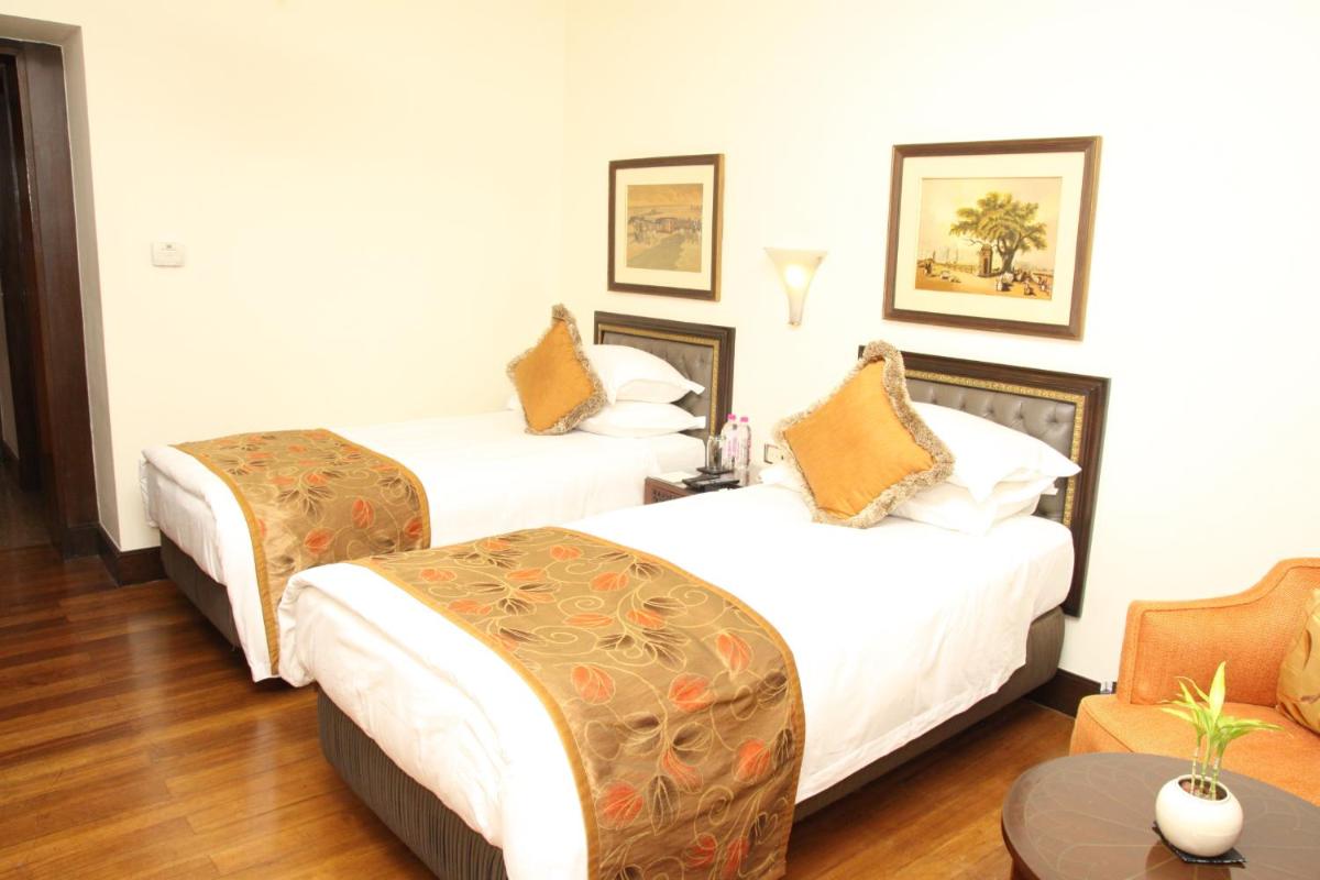 a hotel room with two beds and a table at Taj Bengal in Kolkata