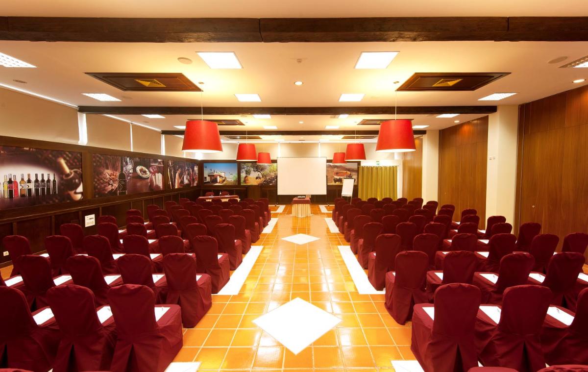 uma sala de conferências com cadeiras vermelhas e um pódio em Vila Gale Alentejo Vineyard - Clube de Campo em Albernoa mais 81 fotografias