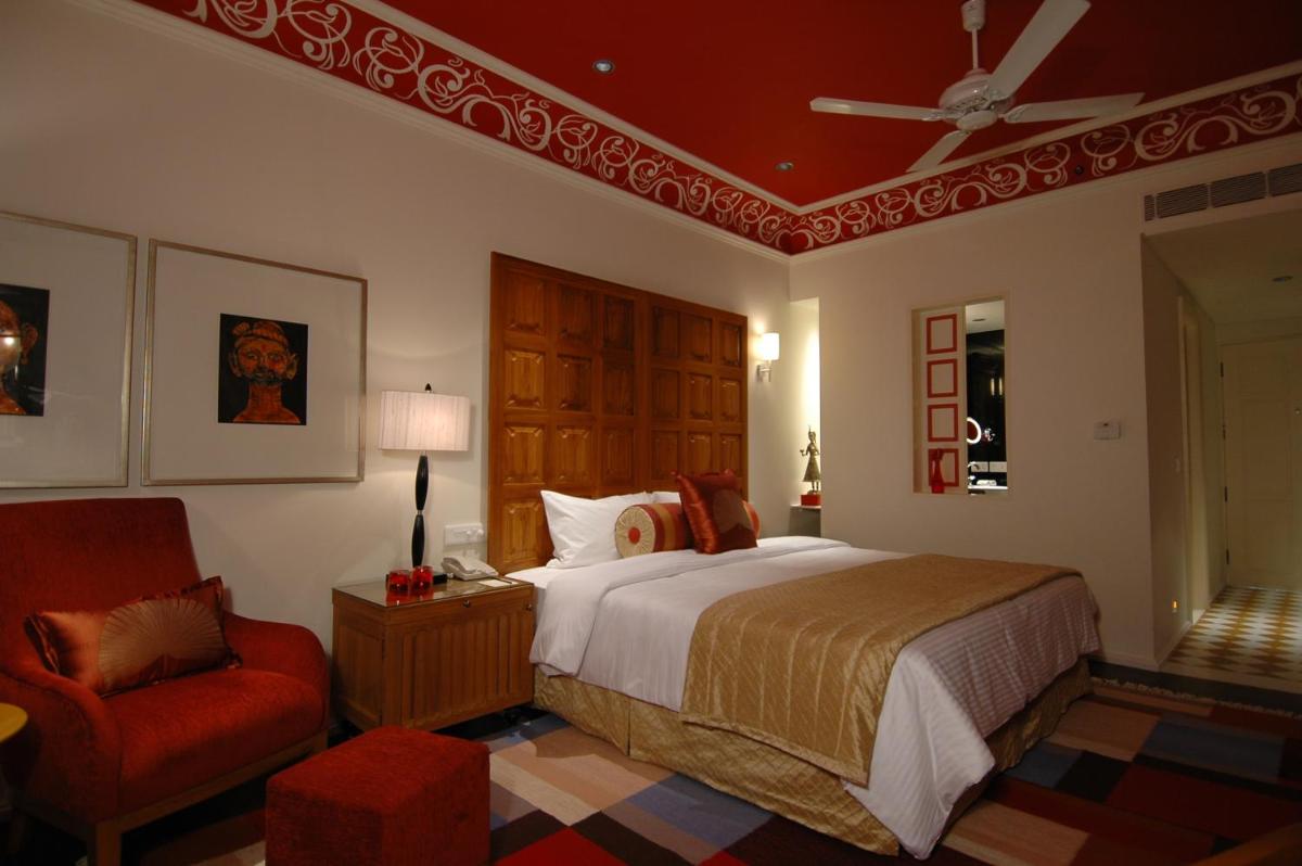 a bedroom with a bed and a red chair at Jai Mahal Palace in Jaipur