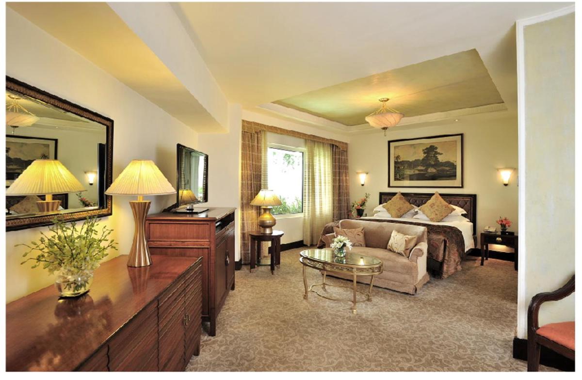 a living room with a bed and a mirror at Taj Bengal in Kolkata