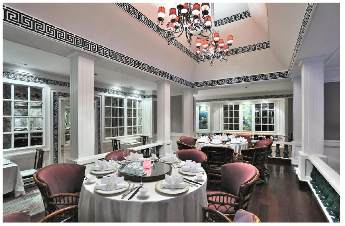 a dining room with tables and chairs and a chandelier at Taj Bengal in Kolkata