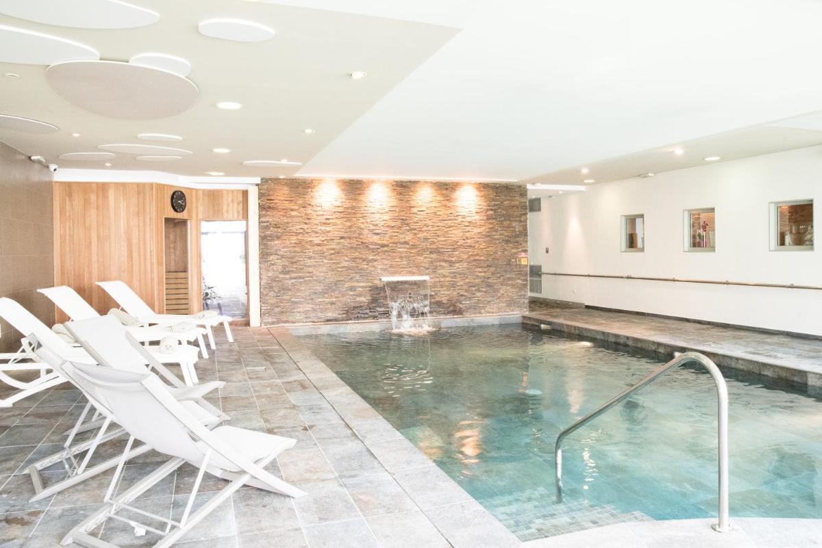 une piscine avec des chaises blanches et une cheminée dans l'établissement Château Belmont Tours by The Crest Collection, à Tours