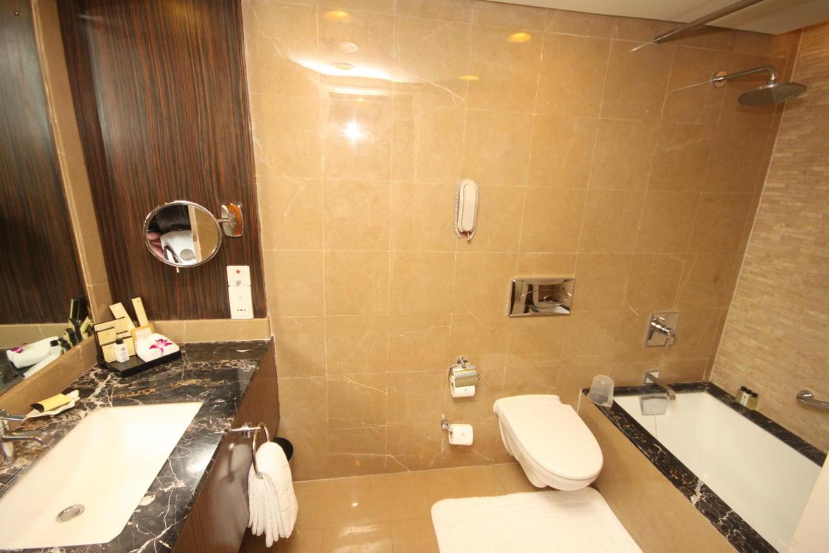 a bathroom with a toilet and a sink and a tub at Taj Bengal in Kolkata