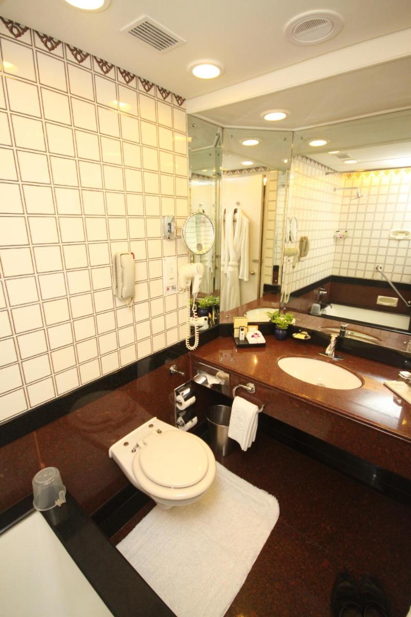 a bathroom with a toilet and a large mirror at Taj Bengal in Kolkata