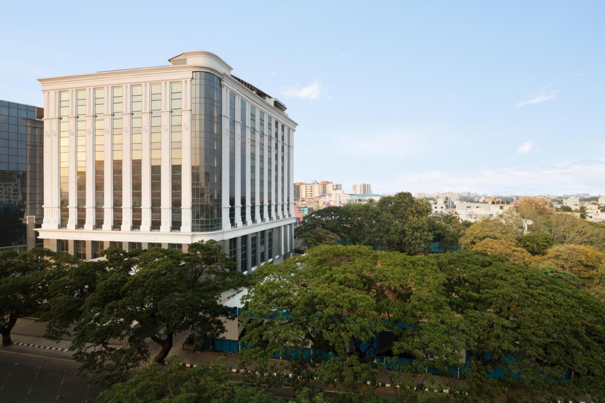 a tall white building with trees in front of it at Ramada Plaza Chennai in Chennai