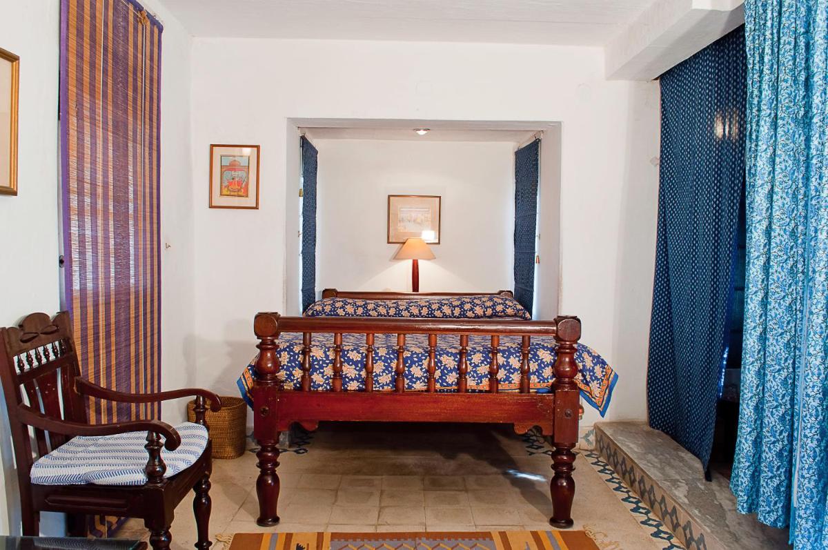 a bedroom with a bed and a chair at Neemrana Fort-Palace in Neemrana