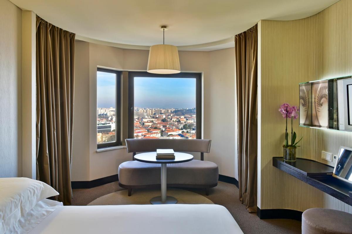 um quarto de hotel com uma cama, uma mesa e uma janela em Porto Palácio Hotel by The Editory no Porto