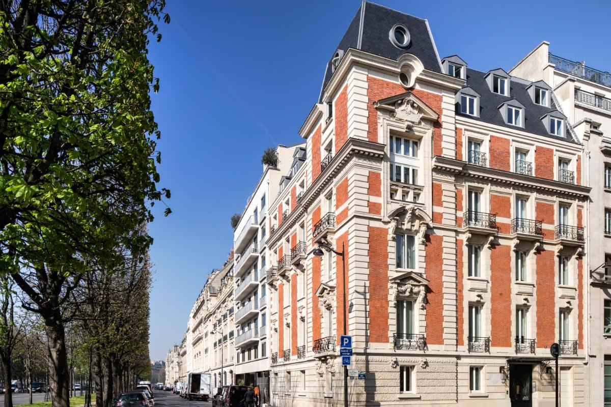 un grand bâtiment en briques rouges avec une tour d'horloge dans l'établissement Le Damantin Hôtel & Spa, à Paris