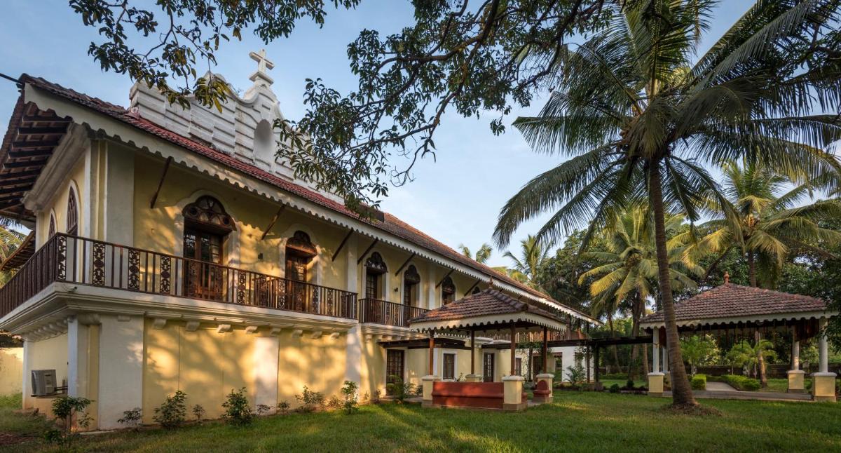 a building with a balcony and a palm tree at The Postcard Cuelim, Goa in Cansaulim