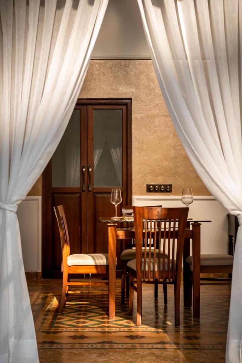 a dining room with a table and chairs and curtains at The Postcard Cuelim, Goa in Cansaulim