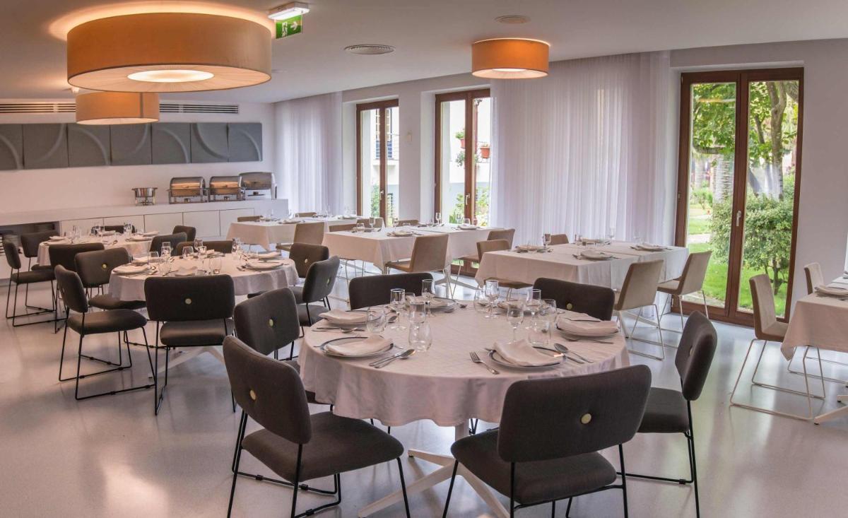 um restaurante com mesas, cadeiras e janelas brancas em Azoris Angra Garden – Plaza Hotel em Angra do Heroísmo