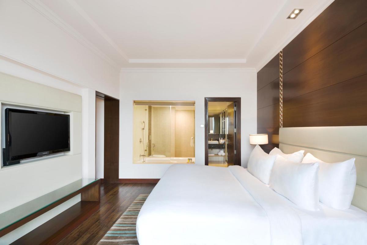 a hotel room with a large bed and a flat screen tv at Radisson Jaipur City Center in Jaipur