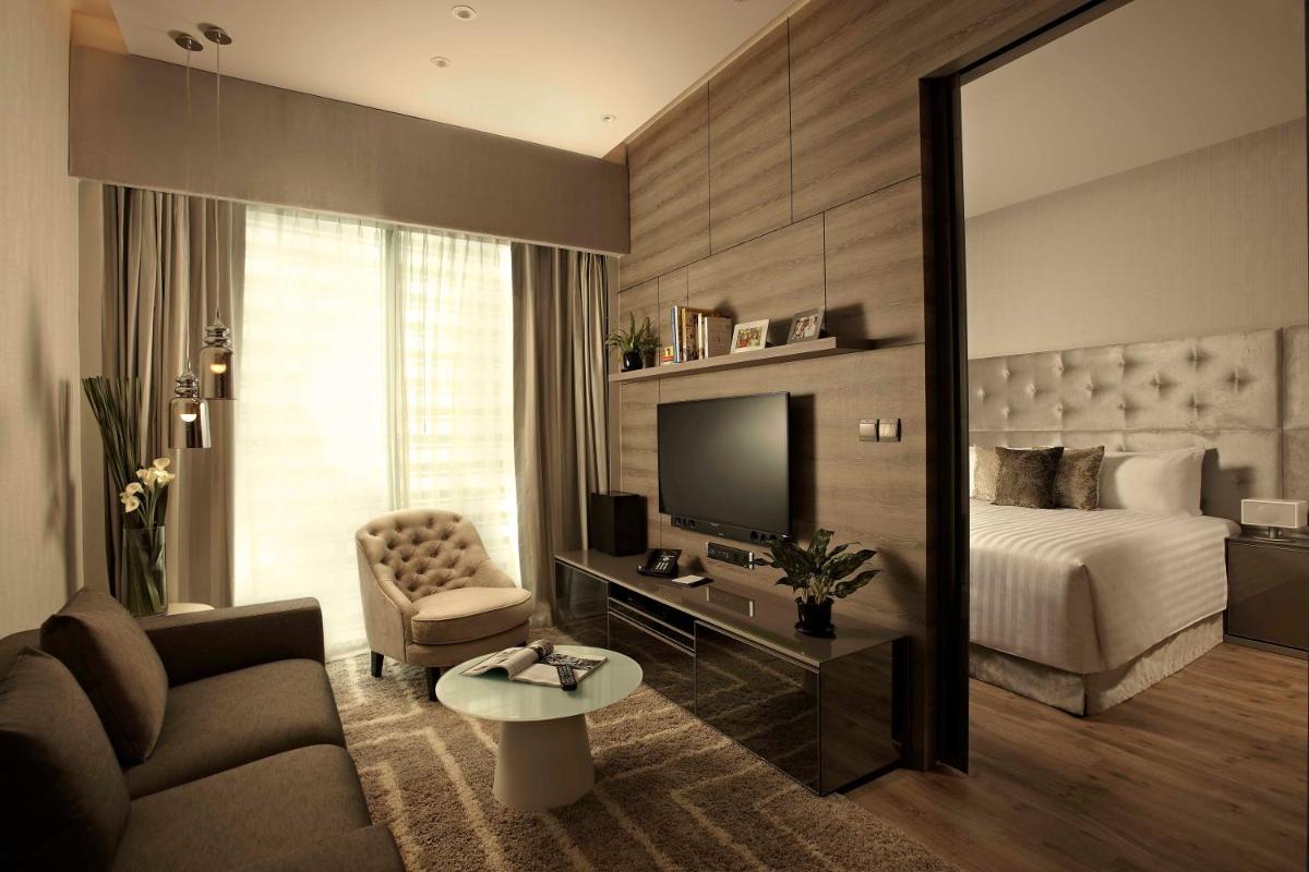 a hotel room with a bed and a couch and a television at Pan Pacific Serviced Suites Beach Road, Singapore in Singapore