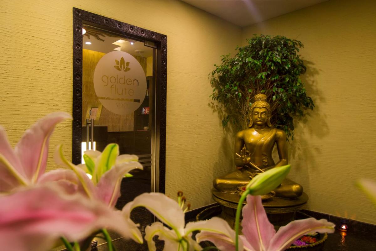 a statue in a room with a mirror and flowers at Sterlings Mac Hotel in Bengaluru