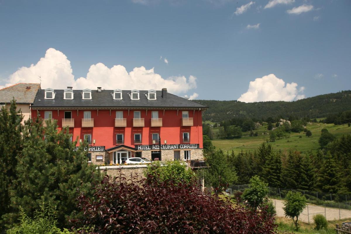 un grand bâtiment rouge avec un toit noir dans l'établissement Hotel Corrieu, à La Llagonne