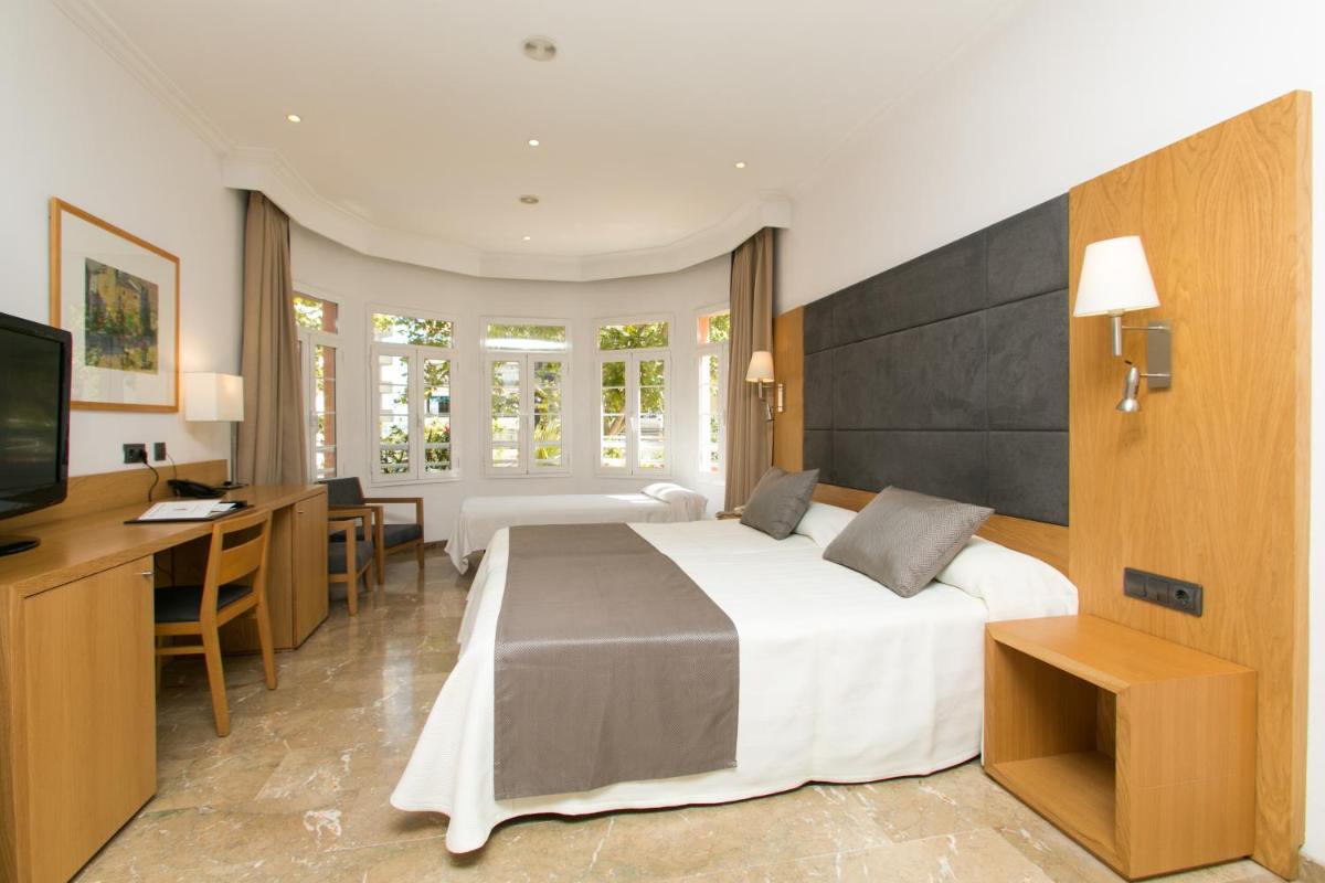 Una habitación de hotel con una cama grande y un escritorio. en Hotel Artmadams, en Palma de Mallorca