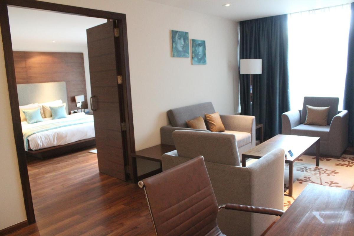 a hotel room with a bed and a living room at Radisson Blu Plaza Hotel Hyderabad Banjara Hills in Hyderabad a hotel room with a bed and a living room at Radisson Blu Plaza Hotel Hyderabad Banjara Hills in Hyderabad