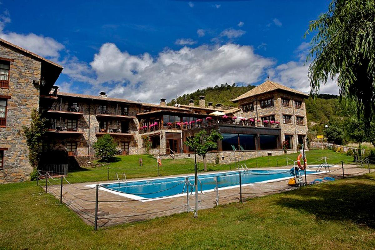 Un gran edificio con una piscina en frente. en Hotel & SPA Peña Montañesa, en Aínsa