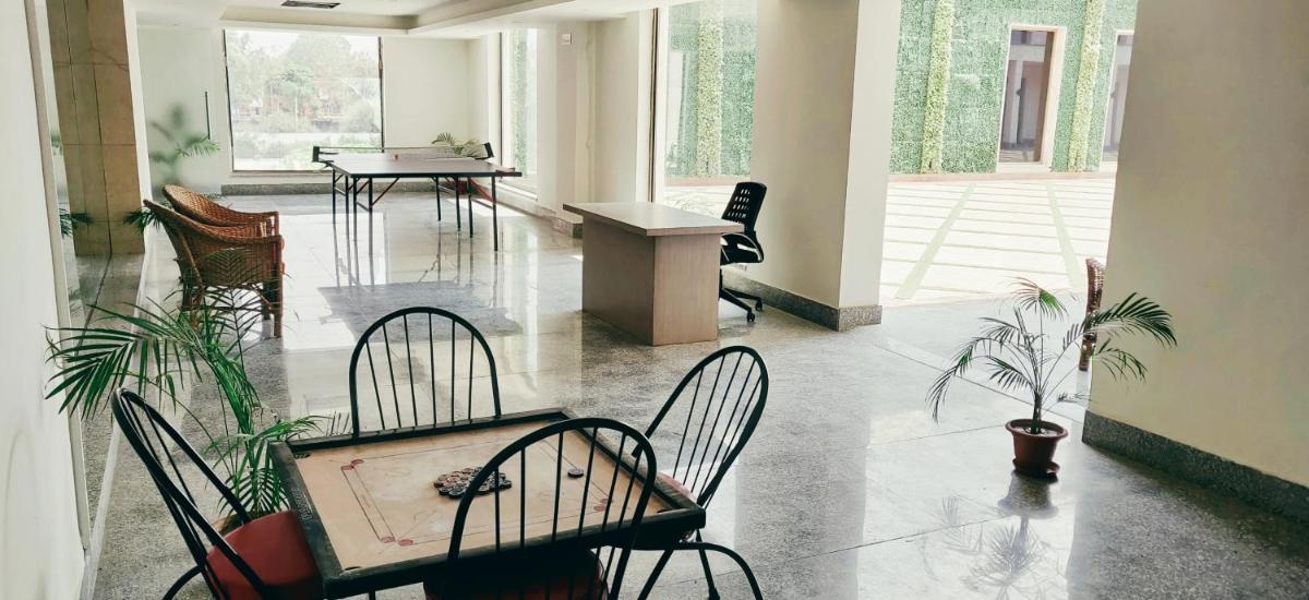 a waiting room with chairs and tables and plants at Ramada by Wyndham Lucknow Hotel and Convention Center in Lucknow