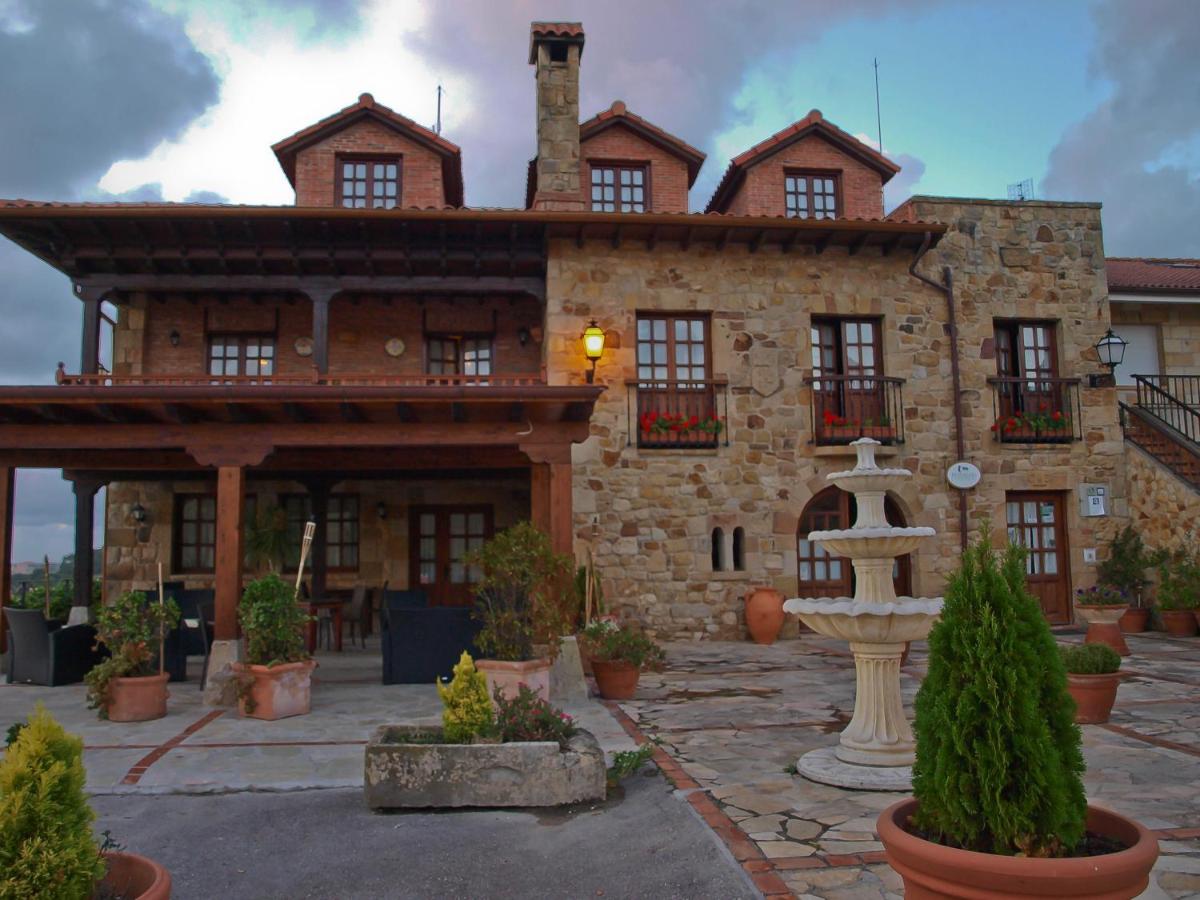 un gran edificio de piedra con una fuente frente a él en Hotel "Posada de Cantabria EL SOLAR" -Cenas típicas y Gintonic- Bar -Terraza panorámica, en Galizano