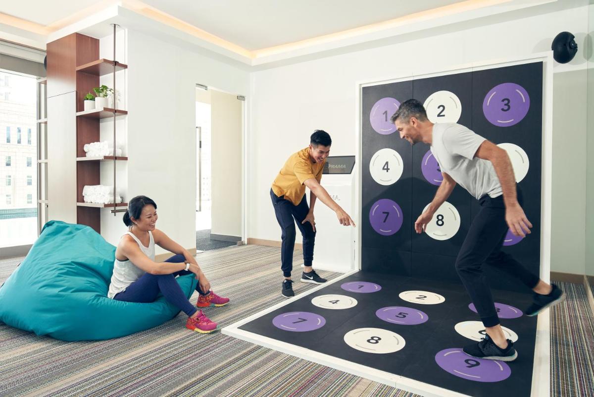 a group of three people playing a game in a living room at Capri by Fraser China Square, Singapore in Singapore a group of three people playing a game in a living room at Capri by Fraser China Square, Singapore in Singapore