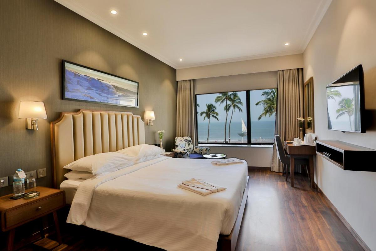 a hotel room with a bed and a desk and a window at Sun-n-Sand Mumbai Juhu Beach in Mumbai