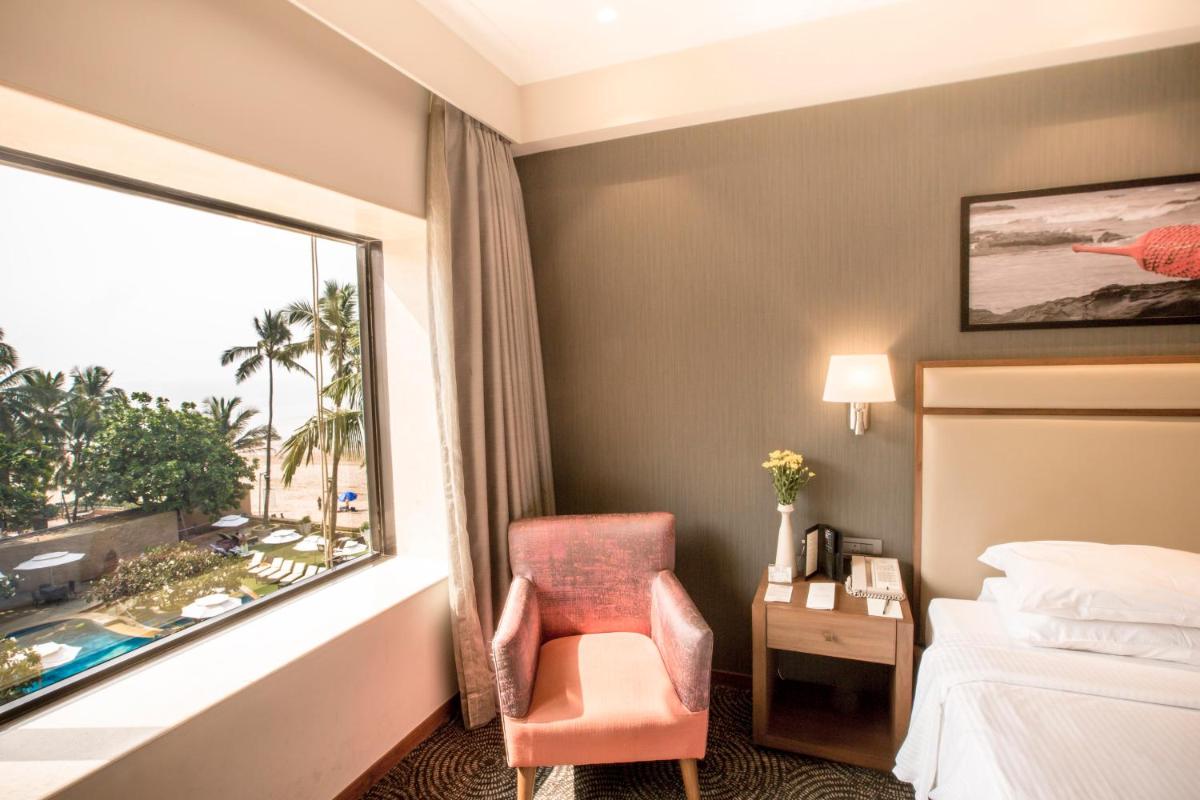 a hotel room with a bed and a chair and a window at Sun-n-Sand Mumbai Juhu Beach in Mumbai