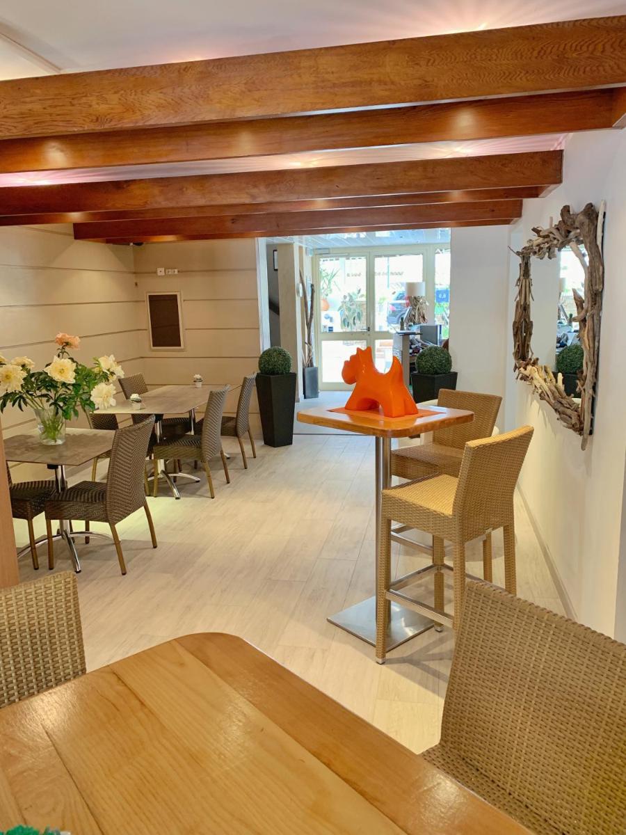 une salle à manger avec des tables et des chaises et un objet rouge sur une table dans l'établissement Hôtel Beau Soleil, au Lavandou
