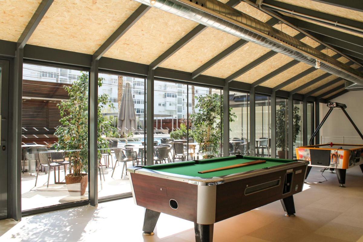 una mesa de billar en medio de una habitación con ventanas en Blaumar Hotel, en Salou