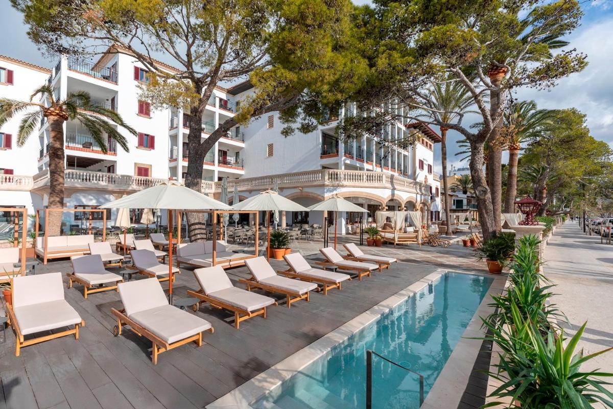 Una piscina tipo resort con tumbonas y sombrillas. en Hoposa Uyal, en Puerto Pollensa