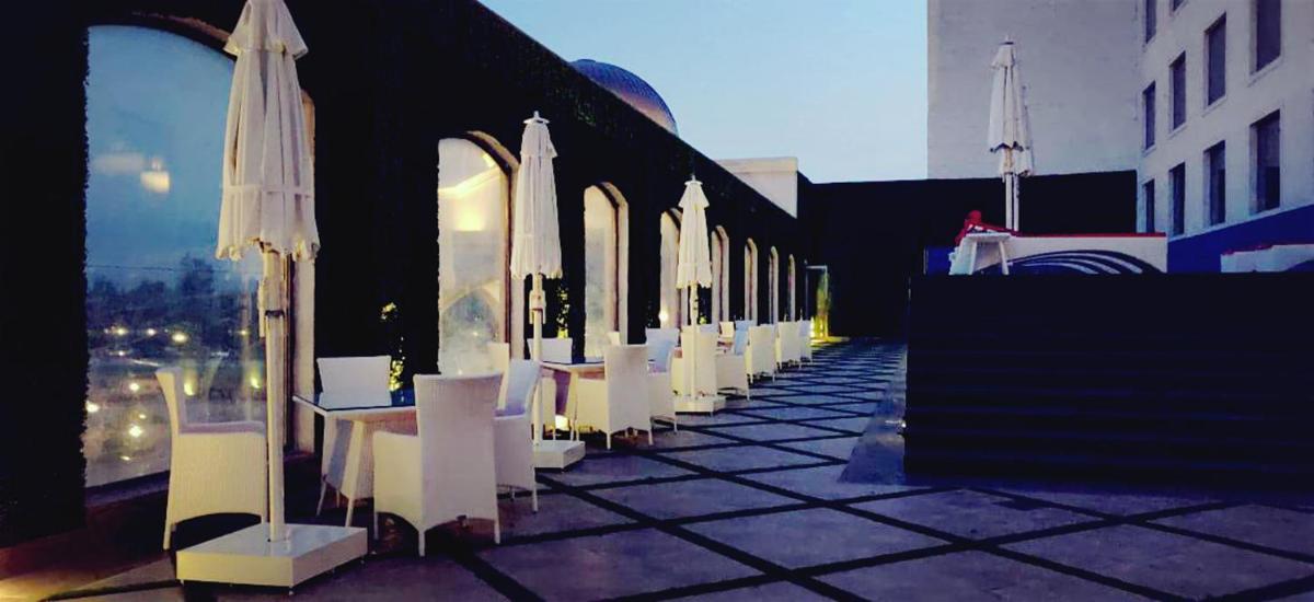 a row of white chairs and umbrellas on a patio at Ramada by Wyndham Lucknow Hotel and Convention Center in Lucknow