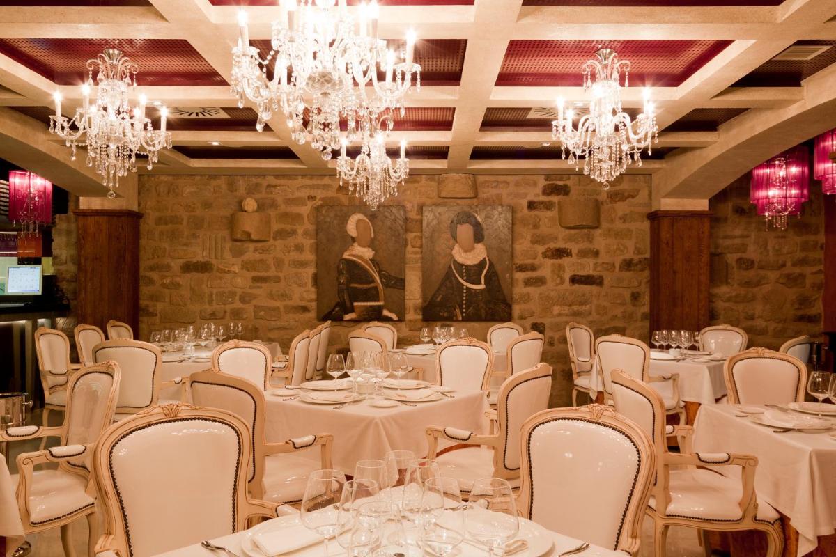 Una habitación con mesas y sillas blancas y candelabros. en Hospederia de los Parajes, en Laguardia