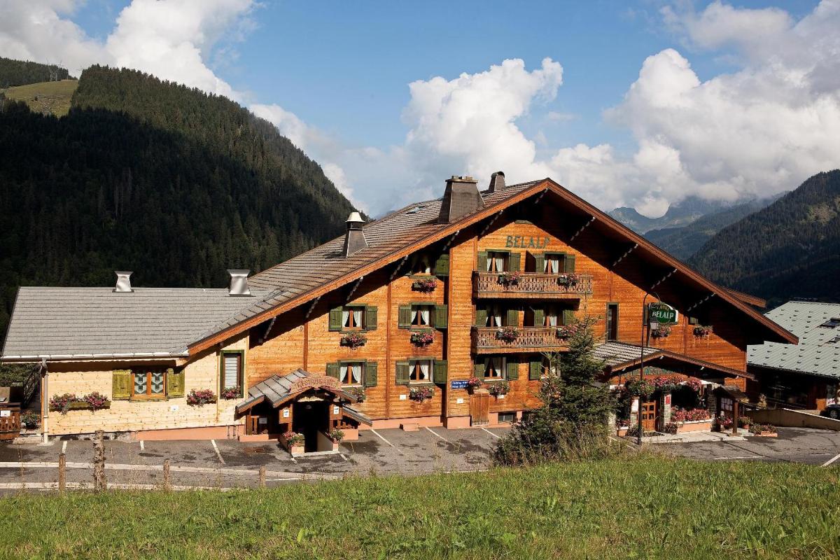 un grand bâtiment en bois avec des montagnes en arrière-plan dans l'établissement Hôtel Belalp, à Châtel